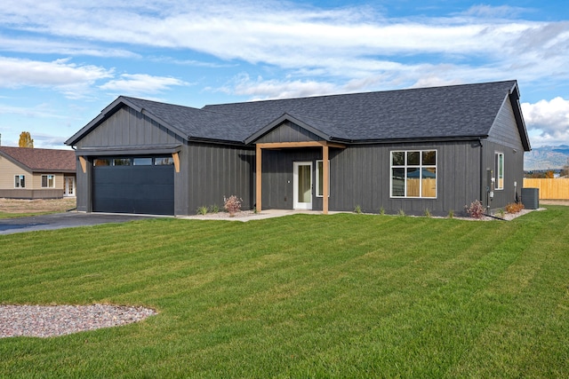 view of front of home featuring a front yard, cooling unit, and a garage