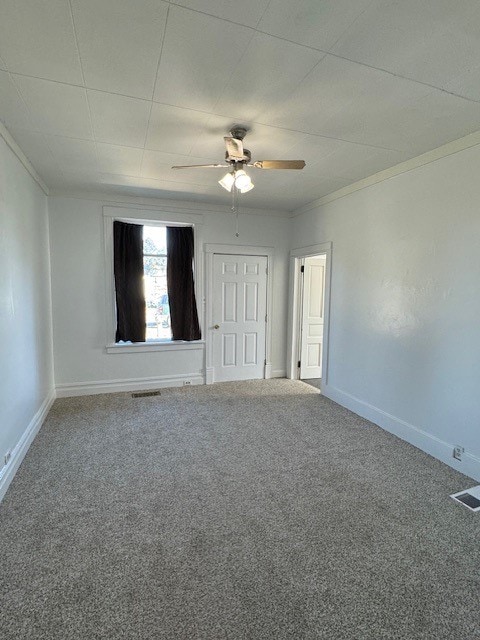 carpeted empty room with ceiling fan and crown molding