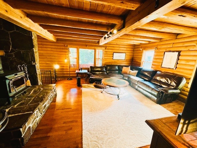 living room featuring wood ceiling, beamed ceiling, log walls, and hardwood / wood-style floors