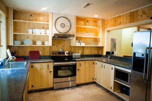 kitchen with wood walls, light brown cabinets, appliances with stainless steel finishes, and sink