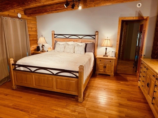 bedroom featuring beamed ceiling and light hardwood / wood-style floors