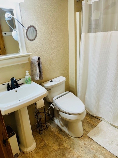 bathroom featuring curtained shower and toilet