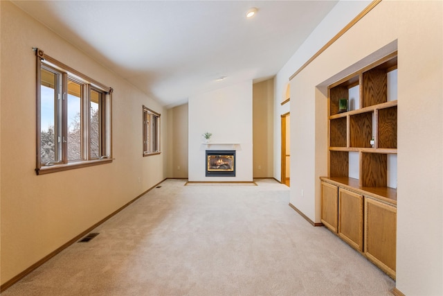 unfurnished living room with light colored carpet and vaulted ceiling