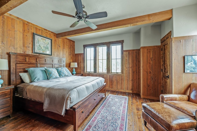 bedroom featuring beam ceiling, ceiling fan, wooden walls, and dark hardwood / wood-style floors