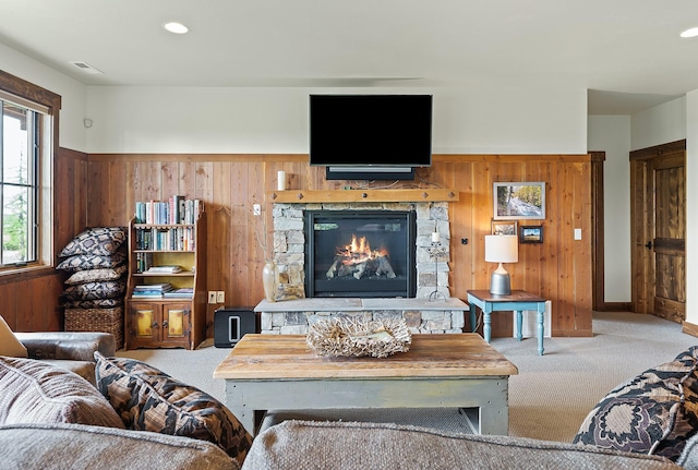 living room featuring wood walls, light colored carpet, and a fireplace