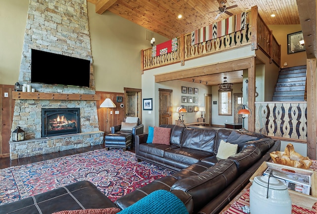 living room with ceiling fan, wooden ceiling, a fireplace, and a towering ceiling