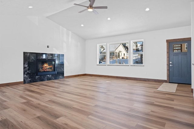 unfurnished living room with ceiling fan, lofted ceiling, a fireplace, and light hardwood / wood-style floors