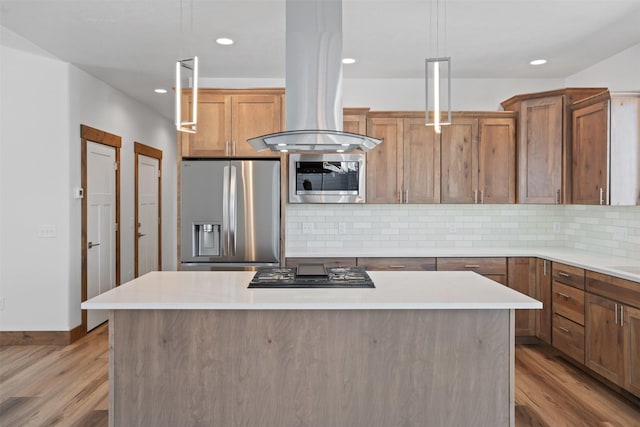 kitchen featuring island range hood, decorative light fixtures, appliances with stainless steel finishes, a kitchen island, and light hardwood / wood-style floors