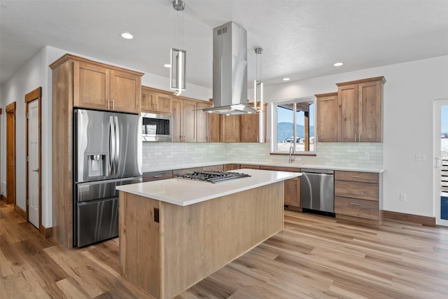 kitchen with sink, island range hood, appliances with stainless steel finishes, a kitchen island, and pendant lighting