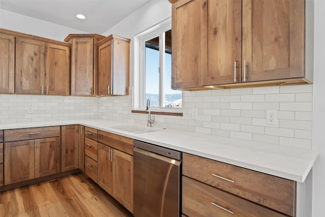 kitchen with dishwasher, sink, decorative backsplash, and light wood-type flooring