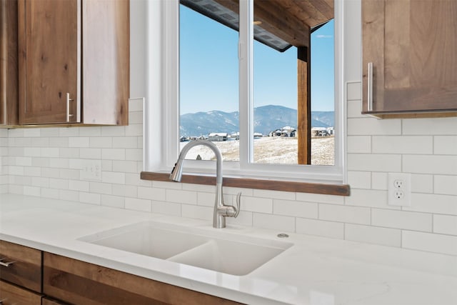 kitchen featuring a mountain view, decorative backsplash, and sink