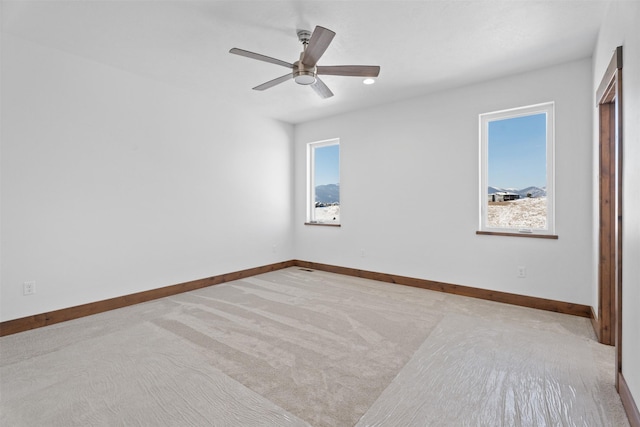 spare room with ceiling fan, a healthy amount of sunlight, and light carpet