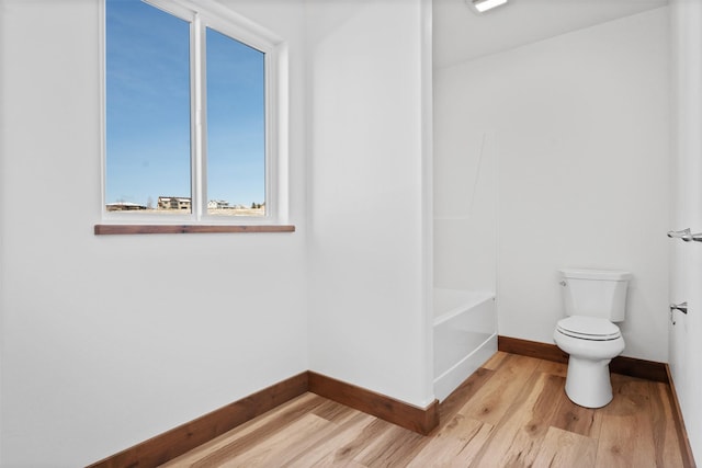 bathroom with wood-type flooring, toilet, and a bathing tub