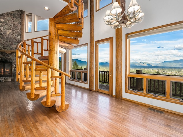 interior space with a stone fireplace, a chandelier, a mountain view, and hardwood / wood-style flooring