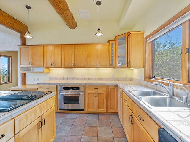 kitchen featuring beamed ceiling, tile countertops, stainless steel oven, black electric stovetop, and sink