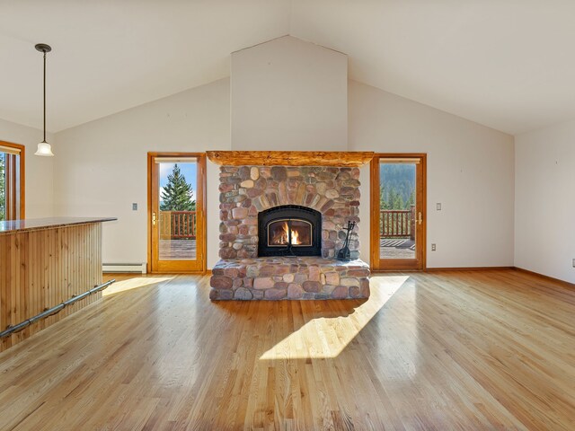 unfurnished living room with a fireplace, plenty of natural light, light hardwood / wood-style floors, and a baseboard heating unit