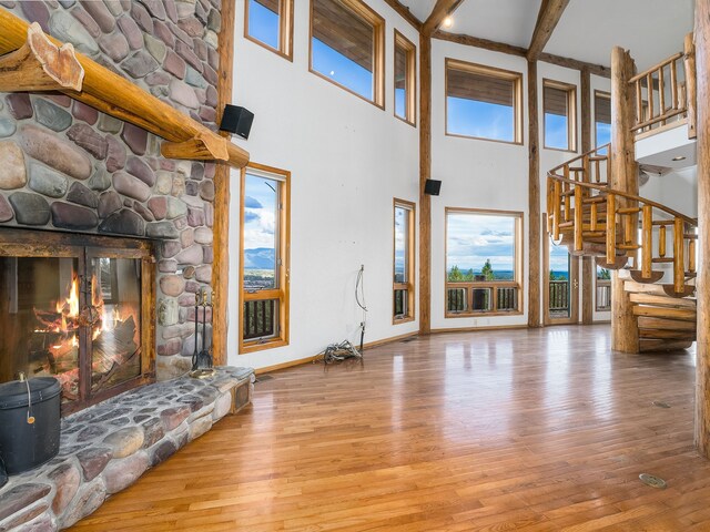 unfurnished living room with light wood-type flooring, a fireplace, beamed ceiling, and a notable chandelier