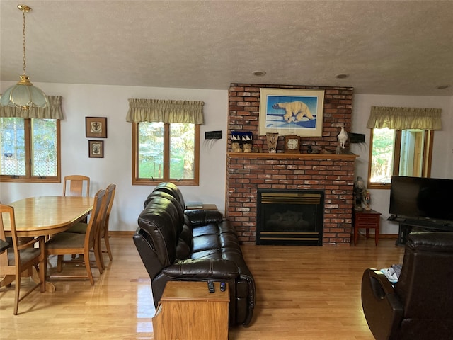 living room featuring light hardwood / wood-style flooring, a wealth of natural light, and a brick fireplace