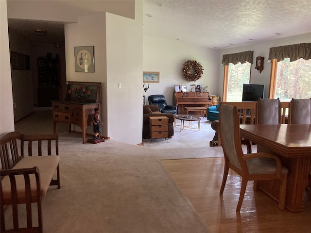 dining space with light carpet and a textured ceiling