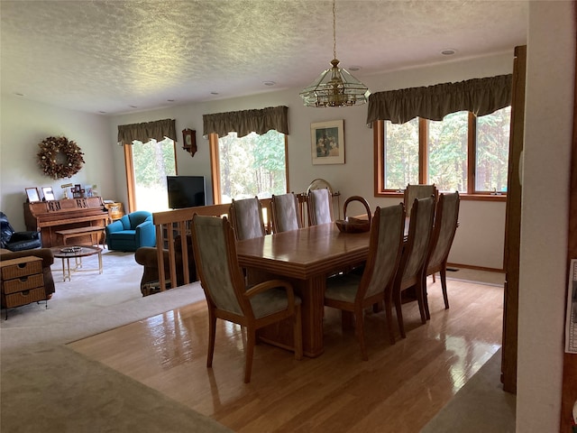 dining room featuring an inviting chandelier, a textured ceiling, and light hardwood / wood-style flooring