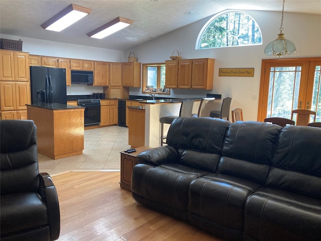 living room featuring light wood-type flooring, a chandelier, sink, high vaulted ceiling, and french doors