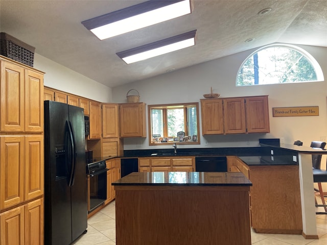 kitchen featuring a kitchen island, lofted ceiling, light tile patterned floors, and black appliances