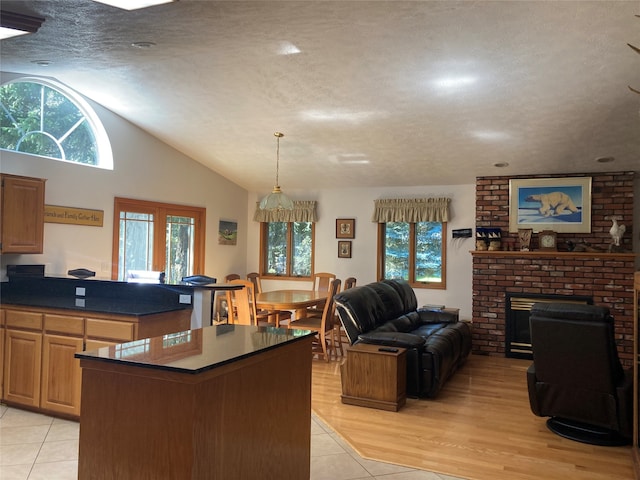 kitchen with a brick fireplace, a textured ceiling, light tile patterned flooring, and a kitchen island