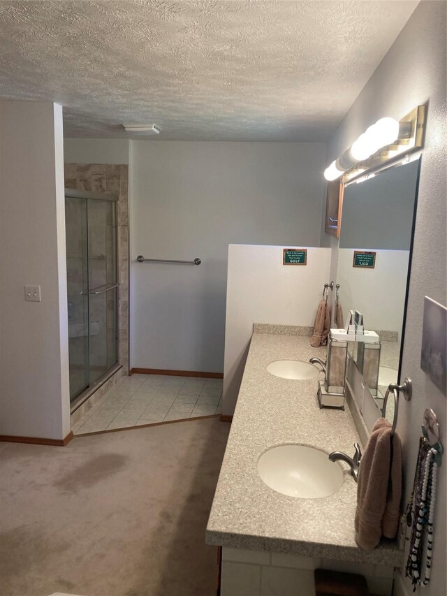 bathroom featuring vanity, tile patterned flooring, a textured ceiling, and an enclosed shower