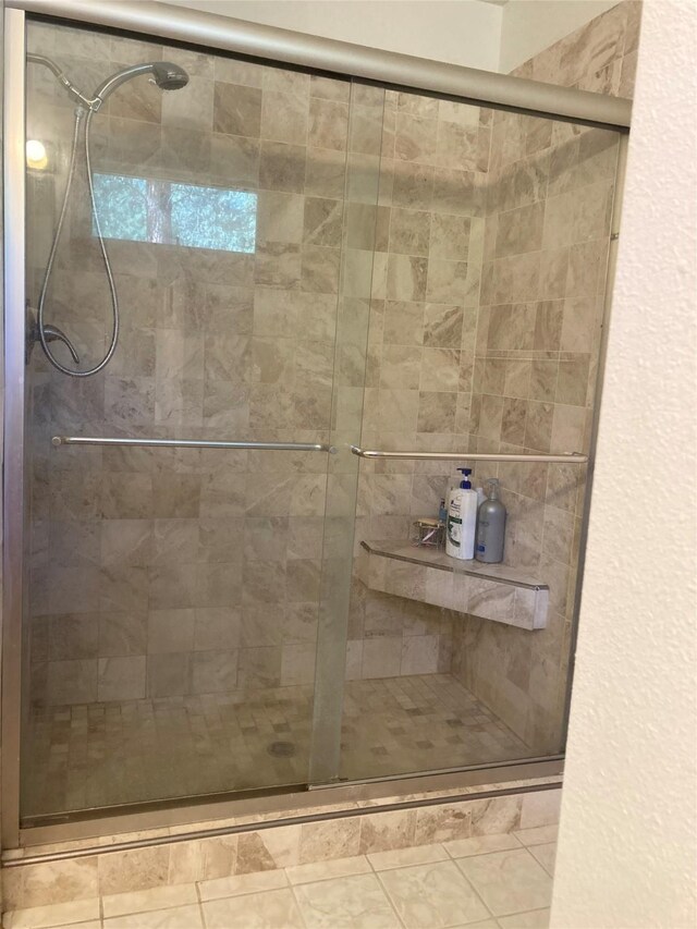 bathroom with an enclosed shower and tile patterned floors