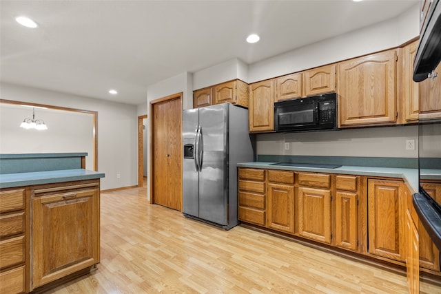 kitchen with pendant lighting, an inviting chandelier, light hardwood / wood-style flooring, and black appliances