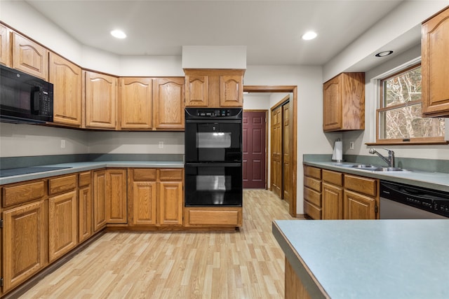 kitchen featuring light hardwood / wood-style flooring, black appliances, and sink