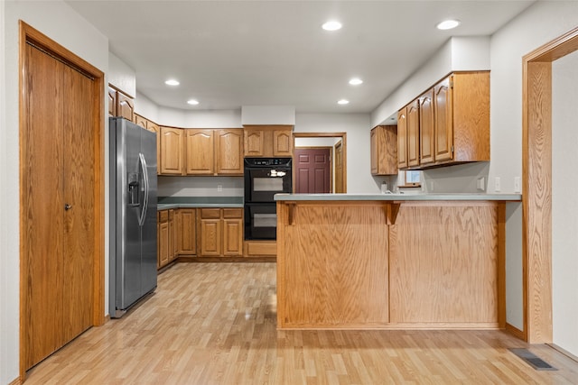 kitchen with double oven, kitchen peninsula, light hardwood / wood-style flooring, and stainless steel refrigerator with ice dispenser