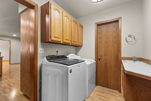 laundry room with washer and dryer, light hardwood / wood-style flooring, cabinets, and sink