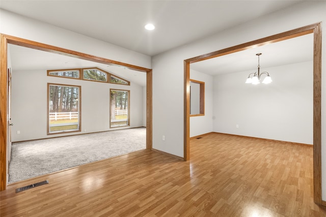 carpeted empty room featuring lofted ceiling with beams and a notable chandelier