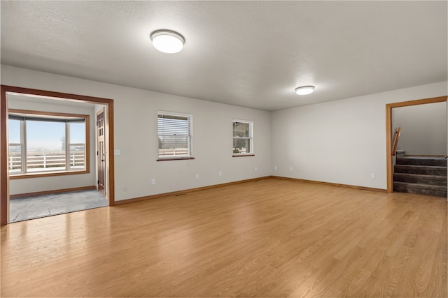 unfurnished living room with light wood-type flooring and a textured ceiling