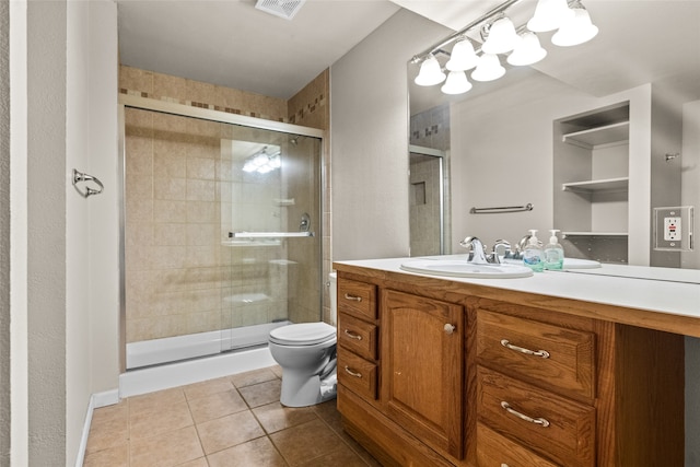 bathroom with tile patterned floors, a shower with door, vanity, and toilet