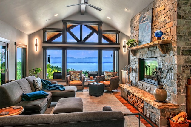 living room with a ceiling fan, a fireplace, wood finished floors, beamed ceiling, and a water view
