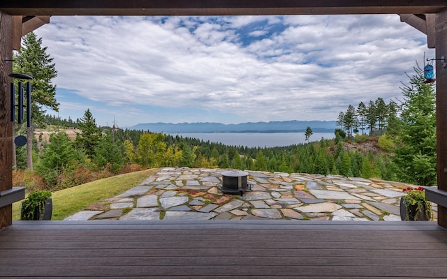 wooden terrace with a patio, a water view, and a fire pit