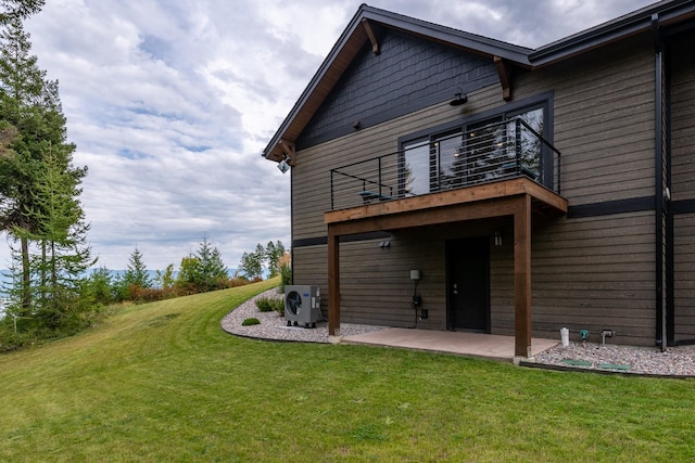 rear view of house featuring ac unit, a patio area, a yard, and a balcony