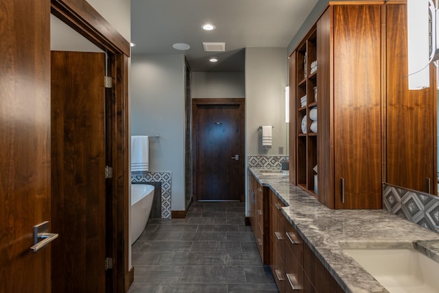 bathroom featuring a sink, double vanity, recessed lighting, a freestanding tub, and visible vents