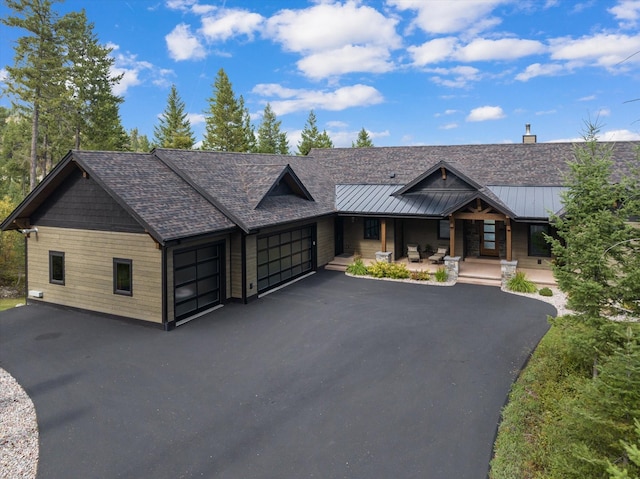 view of front of home featuring a garage, a standing seam roof, metal roof, a porch, and driveway