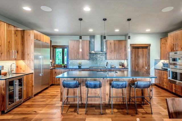 kitchen featuring a sink, beverage cooler, wall chimney exhaust hood, stainless steel appliances, and modern cabinets