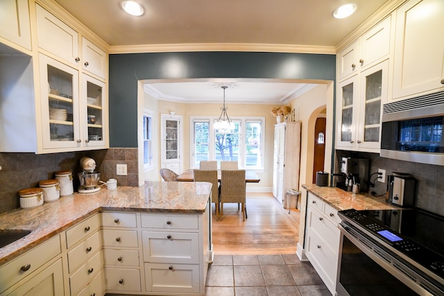 kitchen with decorative light fixtures, appliances with stainless steel finishes, tasteful backsplash, and light stone countertops