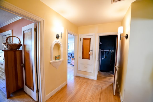 hall with light wood-type flooring and ornamental molding