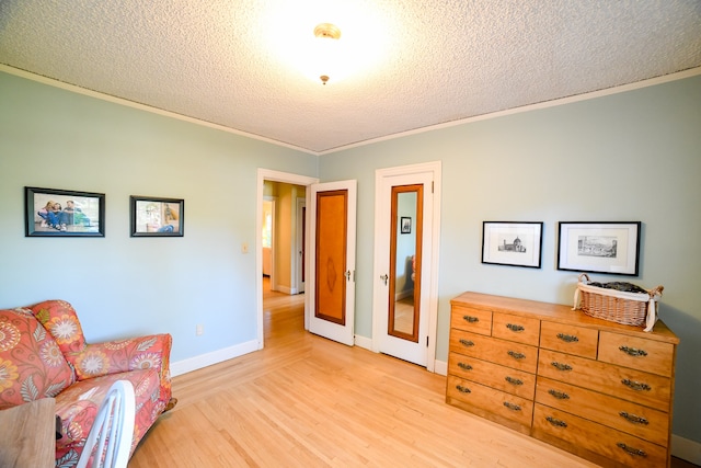 sitting room with a textured ceiling, crown molding, and light hardwood / wood-style flooring