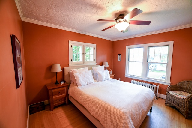 bedroom featuring multiple windows, a textured ceiling, ceiling fan, and radiator heating unit