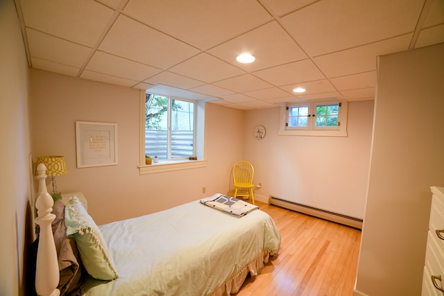 bedroom featuring a baseboard radiator, a paneled ceiling, and light hardwood / wood-style floors