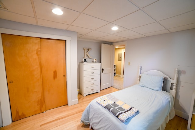 bedroom featuring light hardwood / wood-style flooring, a closet, and a drop ceiling