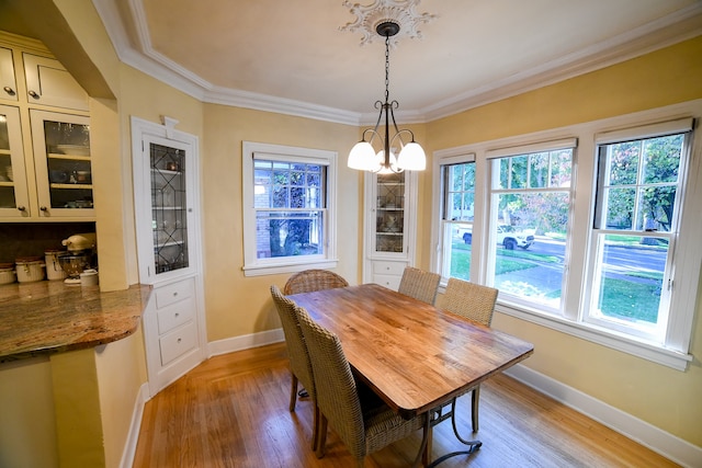 dining area with ornamental molding, light hardwood / wood-style floors, and a notable chandelier