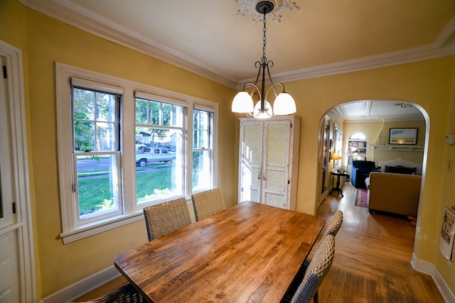 dining area featuring wood-type flooring, crown molding, and a chandelier